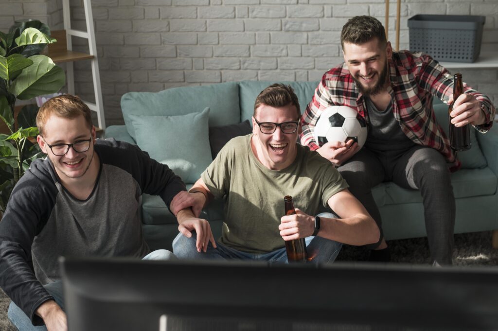 Group of friends watching live soccer match on TV using IPTV service.